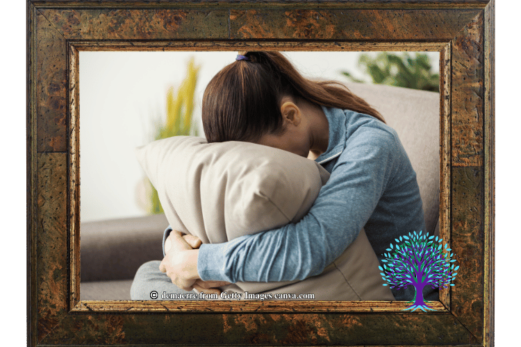Woman with her head in her pillow appearing very sad.