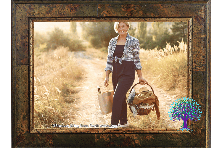 Woman carrying a picnic basket down a dirt road surrounded by fields.