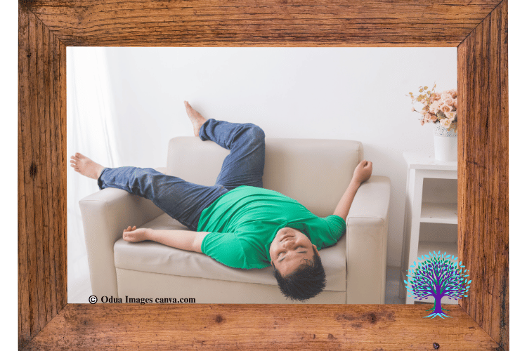 Man with blue pants and green shirt hanging upside down off of couch appearing to be stuck and lazy.